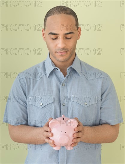 Young man holding piggy bank.