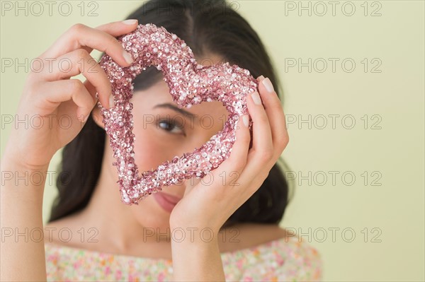 Young woman looking through glittering heart.