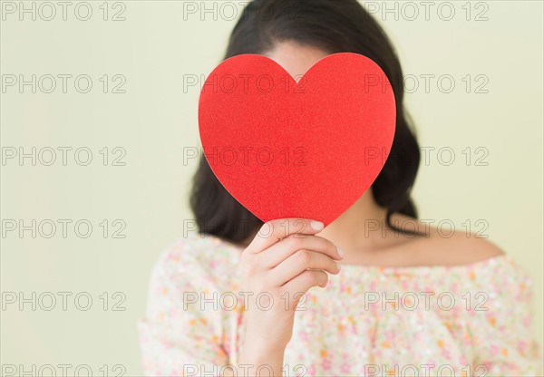 Young woman holding red paper heart.