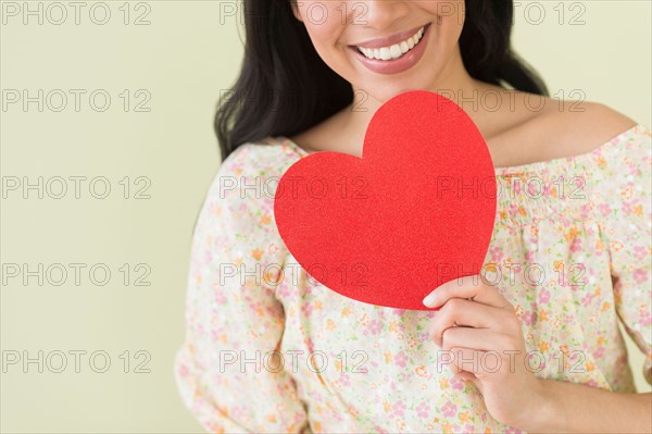 Young woman holding red paper heart.