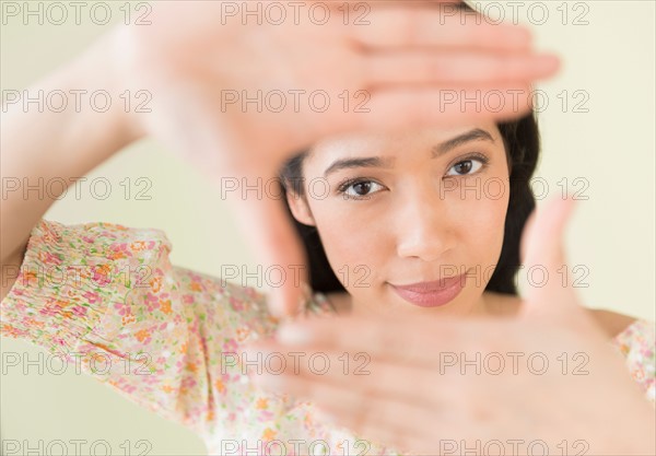 Young woman looking through hand frame.