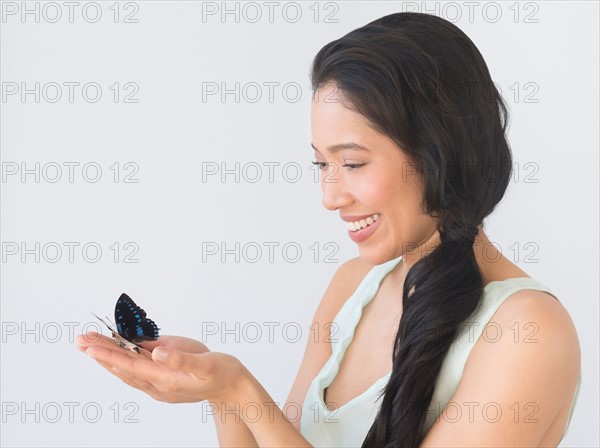 Young woman holding butterfly.