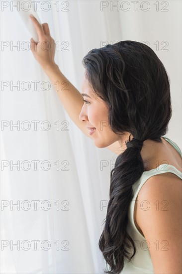 Young woman looking through window.