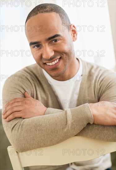 Portrait of young man sitting with arms crossed.