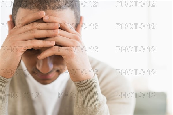 Portrait of young man holding head in hands.