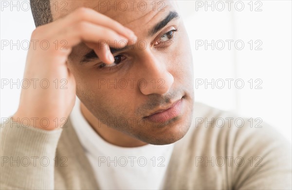 Portrait of young man holding head in hands.