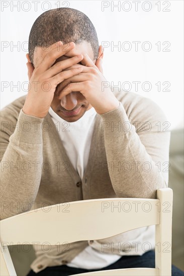 Portrait of young man holding head in hands.