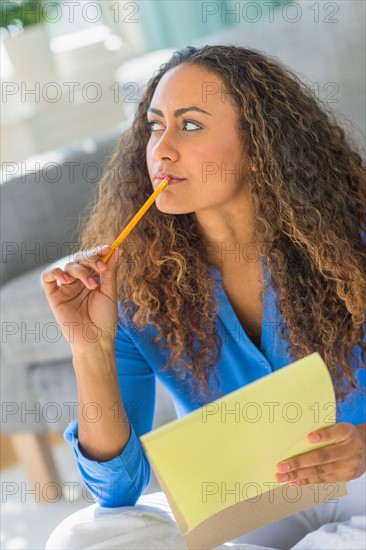 Young woman writing in yellow notepad.