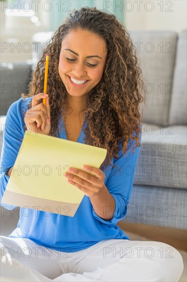 Young woman writing in yellow notepad.