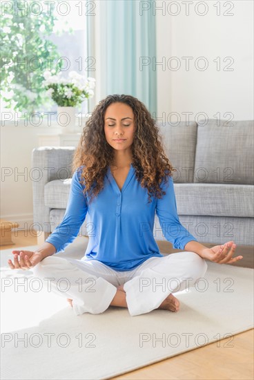 Young woman practicing yoga in living room.