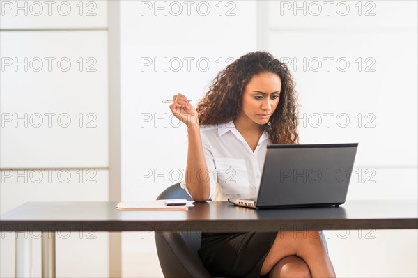 Office worker sitting by desk with laptop.