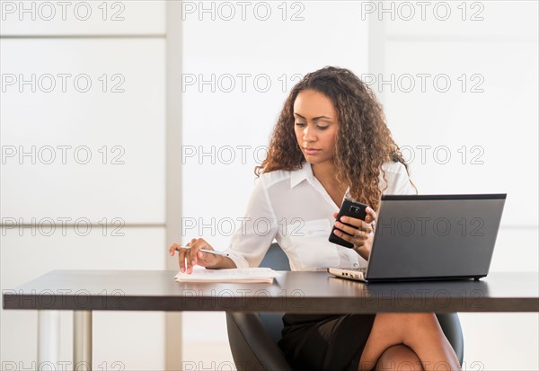 Office worker sitting by desk with laptop.