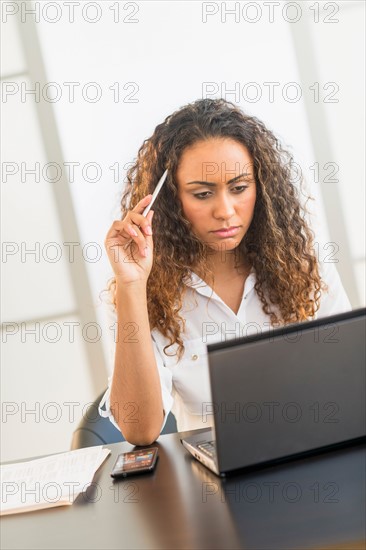 Office worker sitting by desk with laptop.