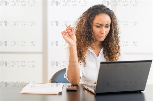 Office worker sitting by desk with laptop.