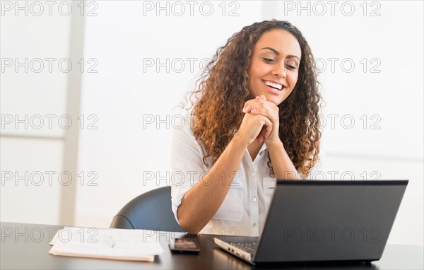 Office worker sitting by desk with laptop.