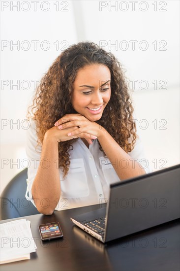 Office worker sitting by desk with laptop.