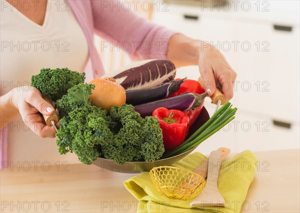 Mature woman holding wok with vegetables