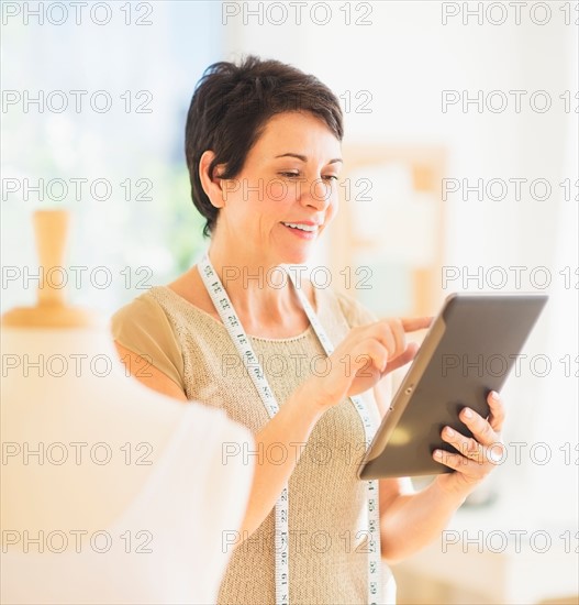 Portrait of mature woman with clothing bust using digital tablet