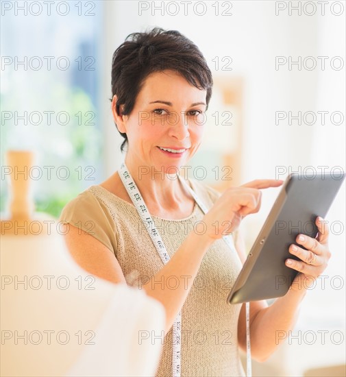 Portrait of mature woman with clothing bust using digital tablet