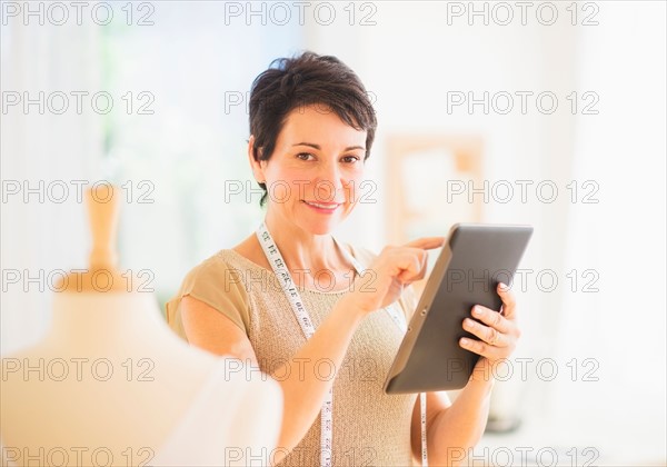 Portrait of mature woman with clothing bust using digital tablet