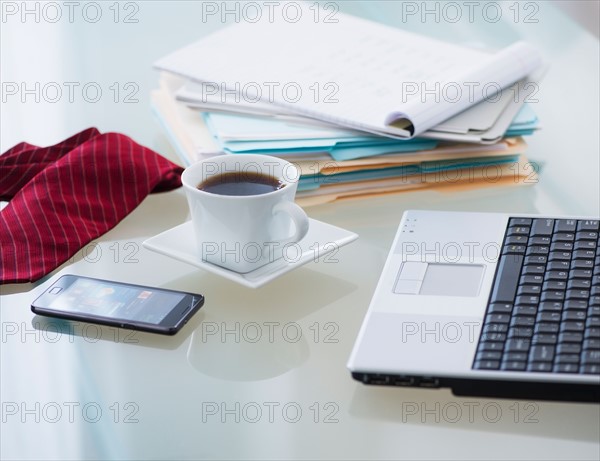 Close-up of coffee, paper material , tie, mobile phone and laptop