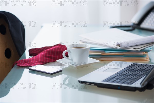 Close-up of coffee, paper material , tie, mobile phone and laptop