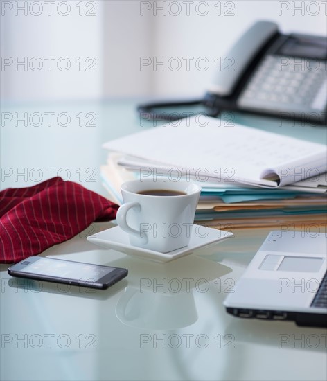 Close-up of coffee, paper material , tie, mobile phone and laptop