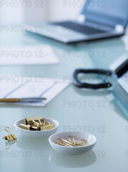 View of paper clips, binder clip, paper material and laptop