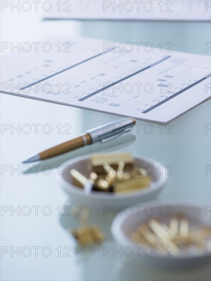 Close-up of paper clip, binder clip, pen and paper material