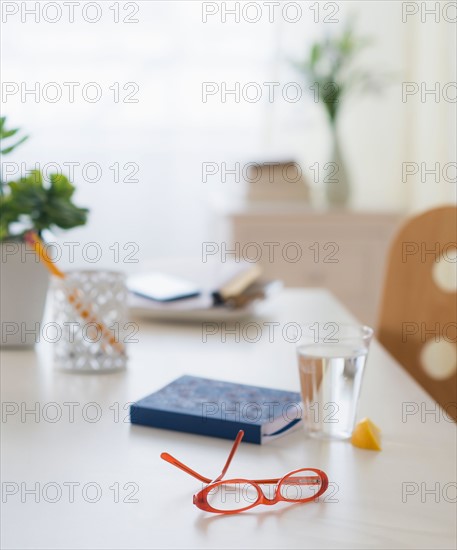 View of spectacles, personal organizer and glass of water on table