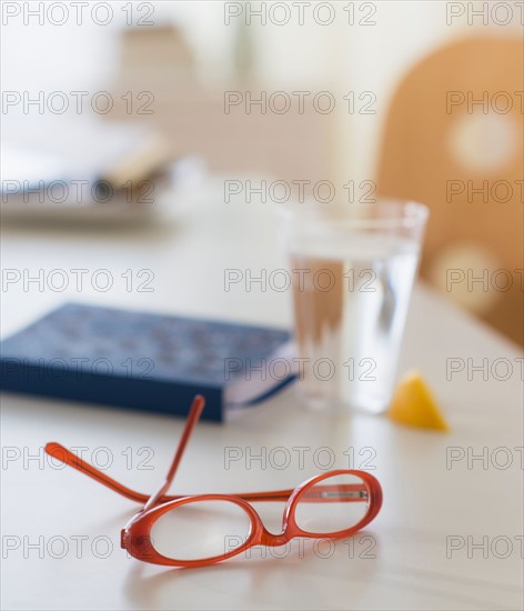 View of spectacles, personal organizer and glass of water on table