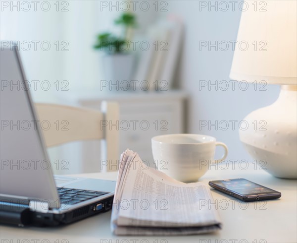 View of newspaper, laptop, mobile phone and cup