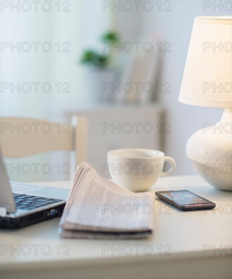 View of newspaper, laptop, mobile phone and cup