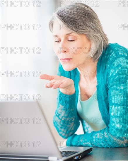 Portrait of woman blowing kiss to computer camera