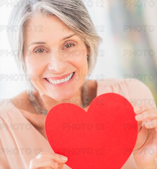 Portrait of woman holding paper heart