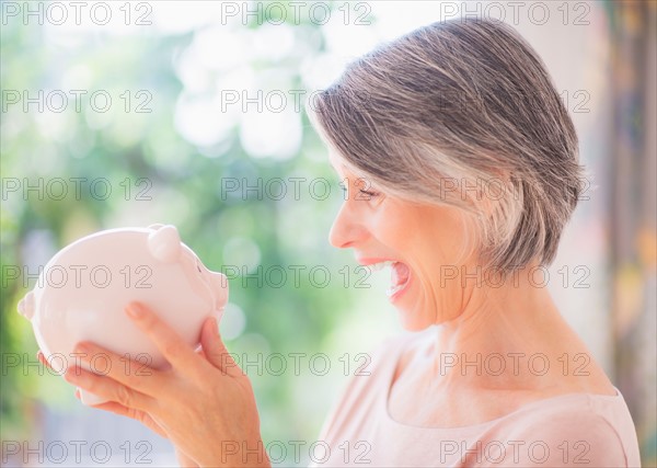 Portrait of excited woman holding piggy bank