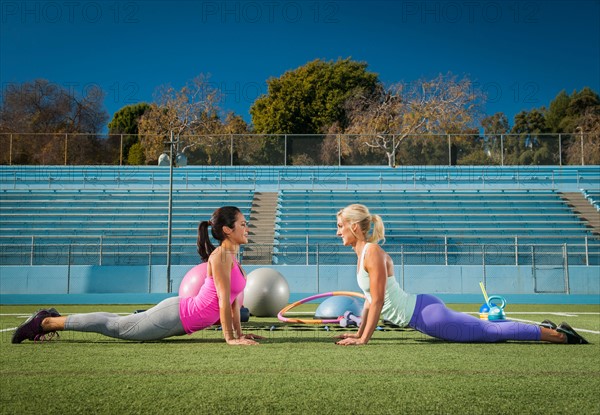 Two women exercising at sports field