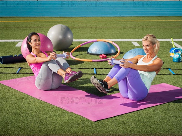 Two women exercising at sports field