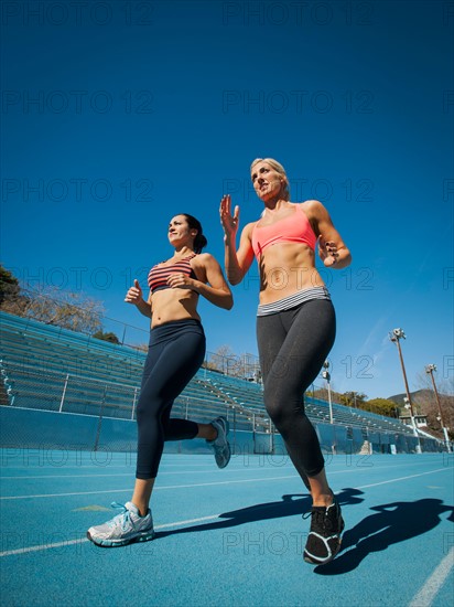 Two women running at sports field