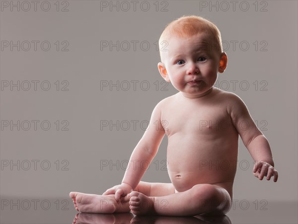 Studio shot of naked baby boy (18-23 months) sitting