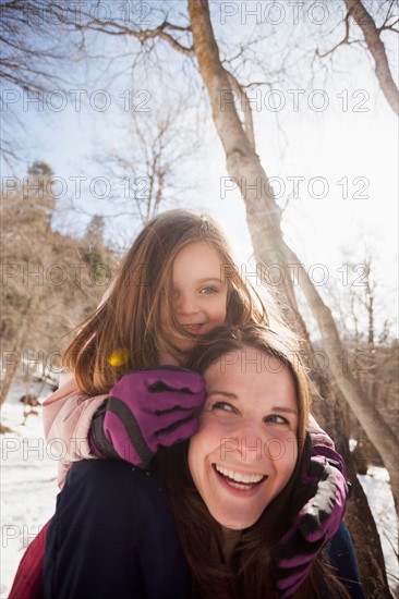 Young woman carrying her daughter (2-3) on shoulders