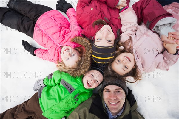 Directly above portrait of three children (2-3, 4-5) with parents lying on snow