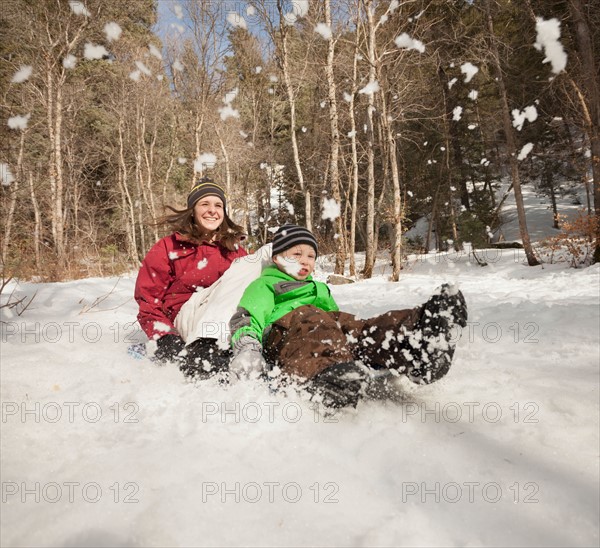 Young woman sledding with boy (4-5)