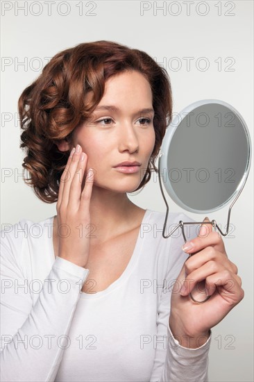 Studio shot portrait of young woman watching herself in mirror