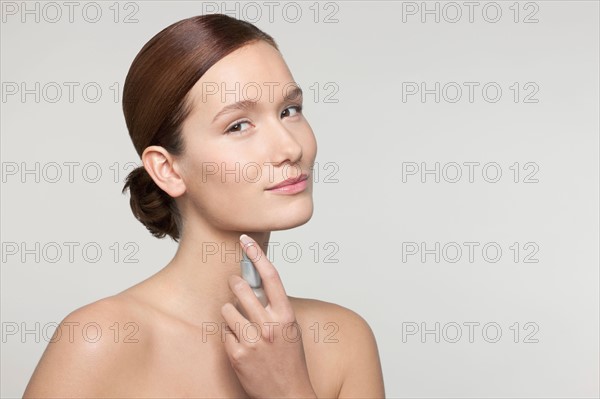 Studio shot portrait of young woman holding perfume