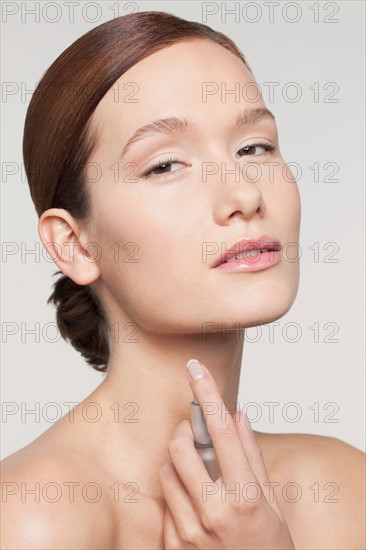 Studio shot portrait of young woman holding perfume