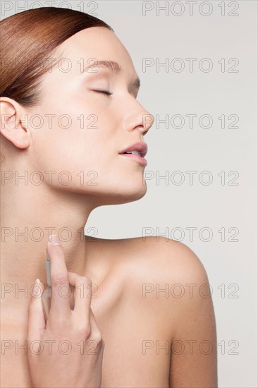 Studio shot portrait of young woman holding perfume