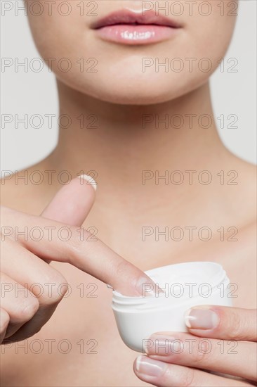 Mid section of young woman applying moisturizer