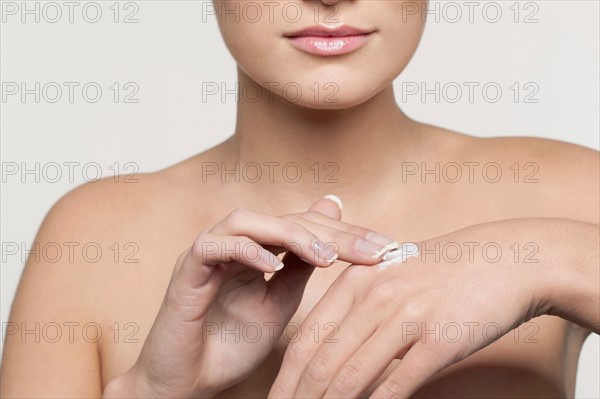 Mid section of young woman applying moisturizer