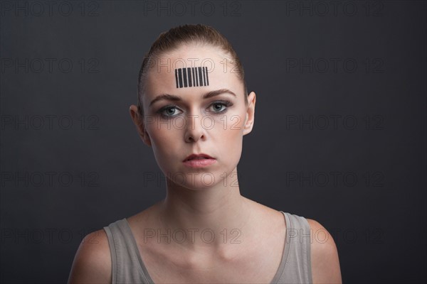 Studio portrait of woman with bar code on forehead